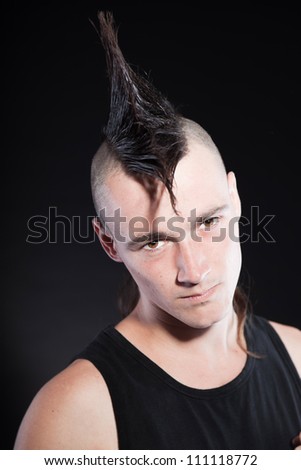 Punk man with mohawk haircut. Black shirt. Expressive face. Isolated on black background. Studio shot.