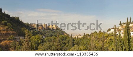 Panoramic photo of the Alhambra. Hill with trees. Blue cloudy sky. Granada. Andalusia. Spain.