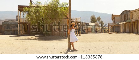 Panoramic photo of brunette female tourist with hat and white dress in western town Fort Bravo. Texas Hollywood. Desierto de Tabernas, AlmeriÃ?Â­a. Andalusia. Spain.