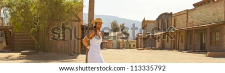 Panoramic photo of brunette female tourist with hat and white dress in western town Fort Bravo. Texas Hollywood. Desierto de Tabernas, AlmeriÃ?Â­a. Andalusia. Spain.