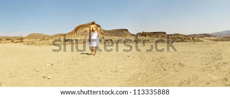 Panoramic photo of brunette female with white dress and hat standing in western landscape with stone arch. Fort Bravo. Texas Hollywood. Desierto de Tabernas, AlmeriÃ?Â­a. Andalusia. Spain.
