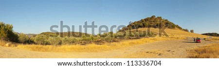 Beautiful panoramic photo of the amazing mountain landscape of Sierra de Grazalema Natural Park at sunset. Golden fields and olive trees. Blue sky. Andalusia. Spain.