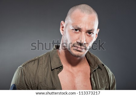 Muscled tough guy wearing green army shirt. Good looking man. Isolated on grey background. Studio shot. Healthy. Fitness.
