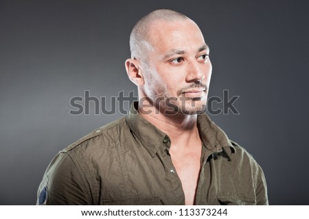 Muscled tough guy wearing green army shirt. Good looking man. Isolated on grey background. Studio shot. Healthy. Fitness.