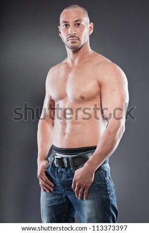 Shirtless muscled fitness man. Cool looking. Tough guy. Brown eyes. Bald. Tanned skin. Studio shot isolated on grey background.