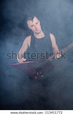 Punk rock man with red electric guitar and mohawk haircut. Expressive face. Isolated on black background. Studio shot.