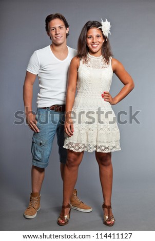 Pretty young couple casual dressed. Brother and sister. Good looking. Brown hair and eyes. Studio portrait isolated on grey background.