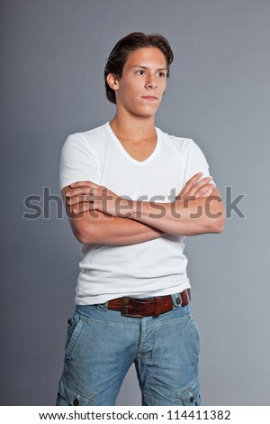 Teenage boy with brown hair and eyes. Wearing white t-shirt and blue shorts. Good looking. Casual wear. Expressions. Studio portrait isolated on grey background.