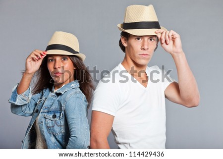 Pretty young couple casual dressed wearing a straw hat. Brother and sister. Good looking. Brown hair and eyes. Studio portrait isolated on grey background.