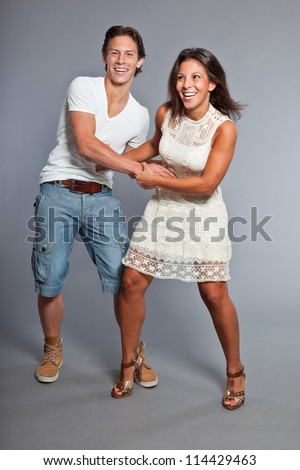 Pretty young couple casual dressed having fun. Brother and sister. Good looking. Brown hair and eyes. Studio portrait isolated on grey background.