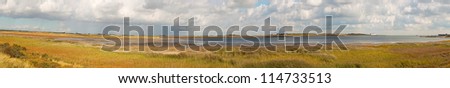 Panoramic shot of dutch landscape with sea and stormy blue cloudy sky. The Mokbaai. Texel. Wadden island. The Netherlands.
