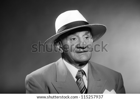 Senior glamour vintage man wearing suit and tie and hat. Black and white studio shot. Gangster look. Isolated.
