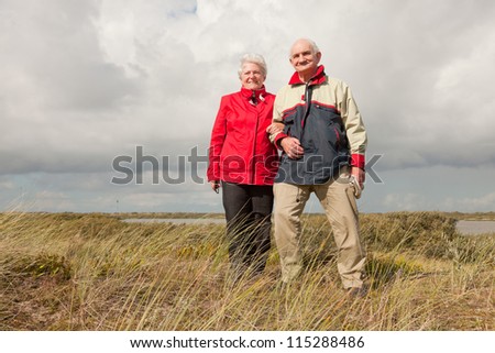 Senior retired couple man and woman enjoying outdoors. Dune landscape with blue cloudy sky. Texel. Wadden island. The Netherlands.