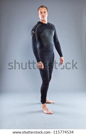 Happy smiling man with short hair wearing wetsuit. Kite surfer. Studio shot. Isolated on grey background.
