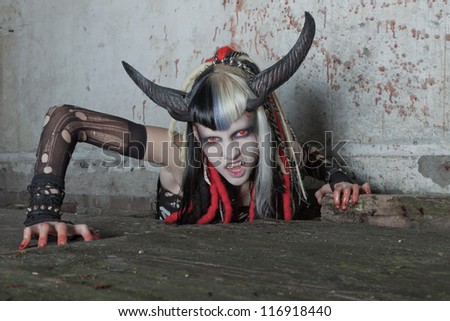 Scary hungry female demon crawling out of the floor. Bloody wall.