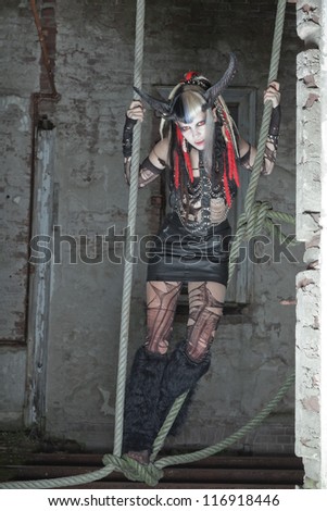 Scary hungry female demon hanging in ropes in old dirty house.