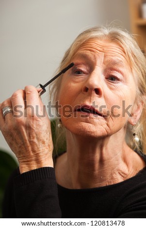 Good looking senior woman doing make-up.