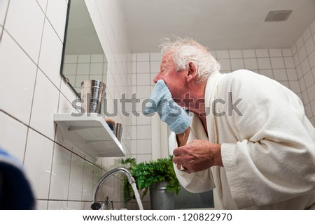Senior man washing his face after shaving.