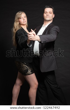 Dancing couple in love. Studio shot against black.