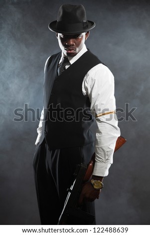 Black american mafia gangster man in suit with gun.