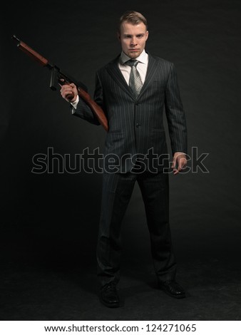 Man in suit shooting with rifle. Studio shot against black.