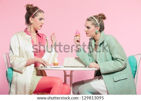 Two girls blonde hair fifties fashion style eating ice cream.
