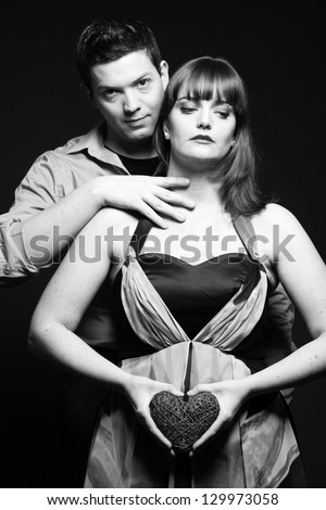 Mysterious couple black and white holding red heart. Studio shot.