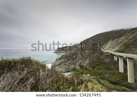 Coast of Big Sur with highway and cloudy sky. USA. California.