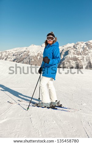 Ski woman in snow mountain landscape with blue sky.
