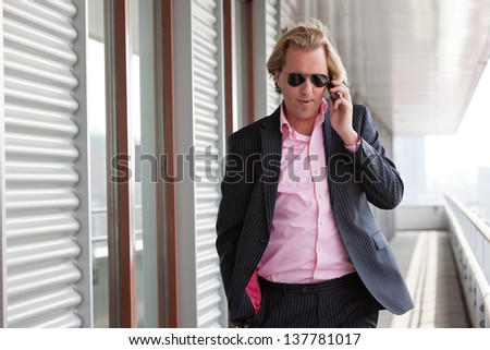 Business man with sunglasses calling with cellphone outdoor at office.