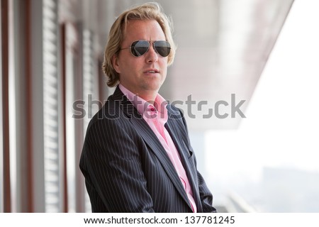 Business man with sunglasses on balcony of office.