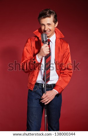 Retro fifties singer wearing red jacket with jeans and tie. Vintage microphone.