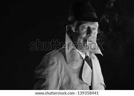 Retro mafia man with hat smoking cigarette. Black and white photo.