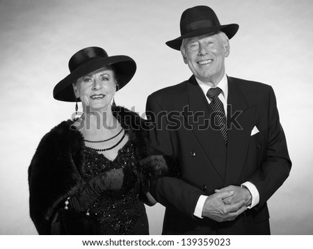 Vintage glamour senior couple wearing black hat. Black and white photo.