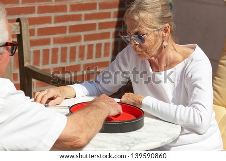 Senior couple playing dice game outdoor in garden. Yahtzee.