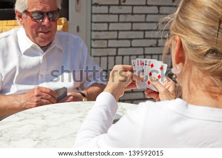 Senior couple playing card game outdoor in garden.