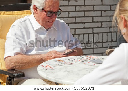 Senior couple playing card game outdoor in garden.