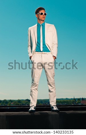 Retro Fifties Summer Fashion Man With White Suit And Sunglasses. On Rooftop. Blue Sky.