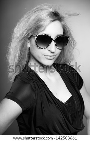 Beauty portrait of pretty girl with long blonde hair and sunglasses. Black and white shot.