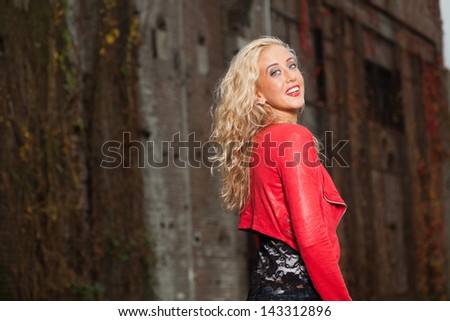 Handsome young woman with long blonde hair and red jacket. Urban fashion.