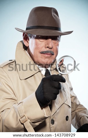 Retro detective man with mustache and hat. Holding magnifying glass. Studio shot.