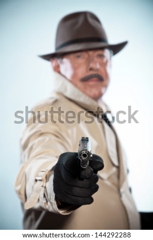 Retro detective with mustache and hat. Holding gun. Studio shot.