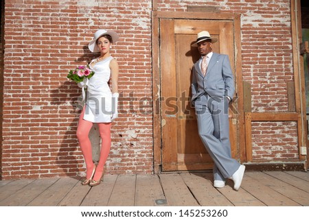 Vintage jazz fashion sexy wedding couple in old urban building. Mixed race. Wearing a hat.