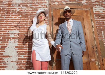Vintage jazz fashion sexy wedding couple in old urban building. Mixed race. Wearing a hat.