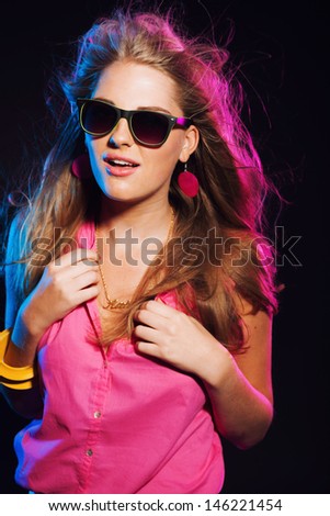 Sensual retro 80s fashion disco girl with long blonde hair and sunglasses. Black background.