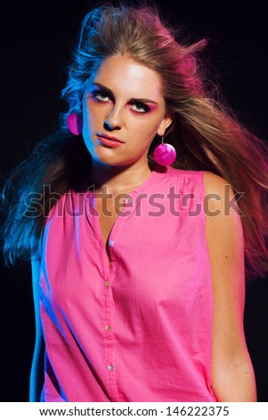 Sexy vintage 80s fashion disco girl with long blonde hair. Black background.