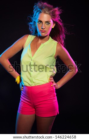 Cool vintage 80s fashion disco girl with long blonde hair and green shirt. Black background.