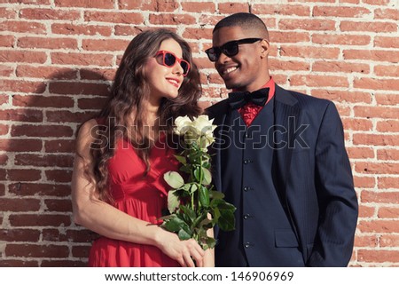 Urban cool retro fashion mixed race wedding couple wearing black suit and red dress and sunglasses.