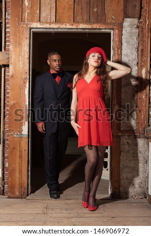 Vintage fashion mixed race wedding couple wearing black suit and red dress. Interior of old house.