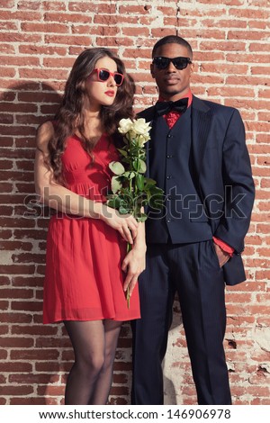 Urban cool retro fashion mixed race wedding couple wearing black suit and red dress and sunglasses.